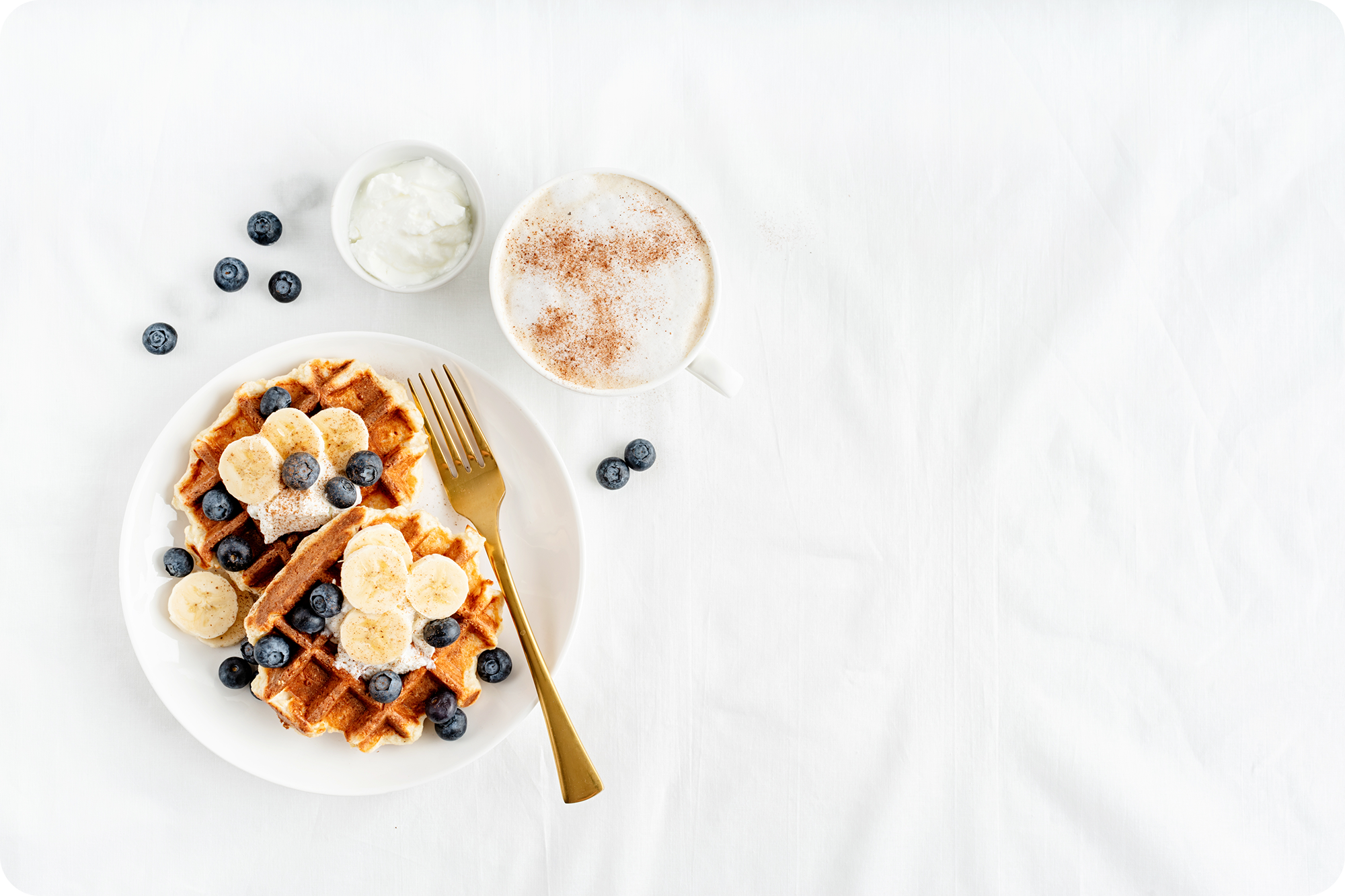 Gezond ontbijt met wafels, banaan, blauwe bessen en yoghurt als onderdeel van een gebalanceerd voedingspatroon.