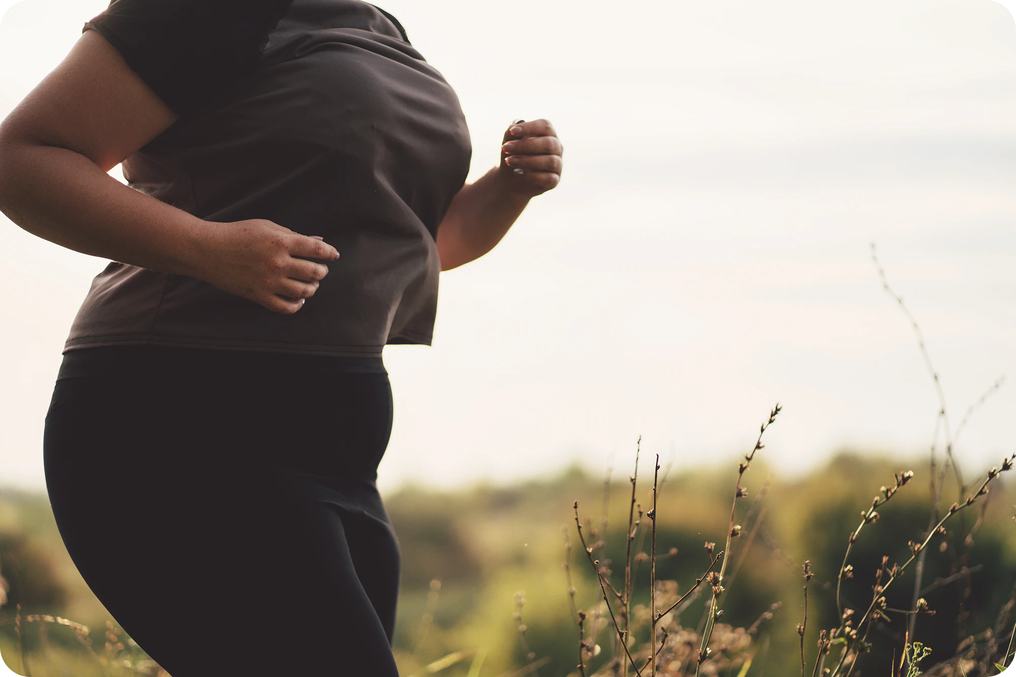 Vrouw jogt buiten in de natuur als onderdeel van een gezonde leefstijl met realistische doelen.